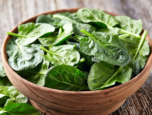 Eine Tonschale enthält grünen ungekochten Blattspinat